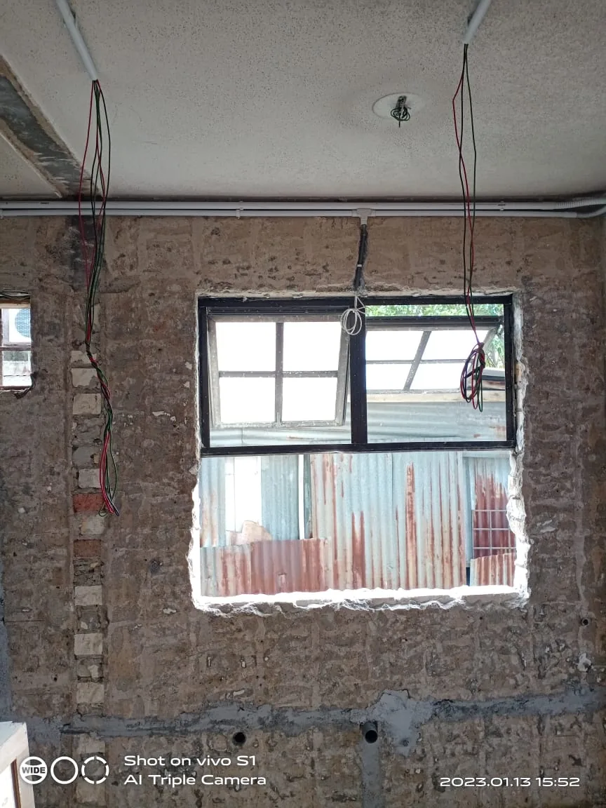 Loose cable drops around a window in an exposed brick wall.