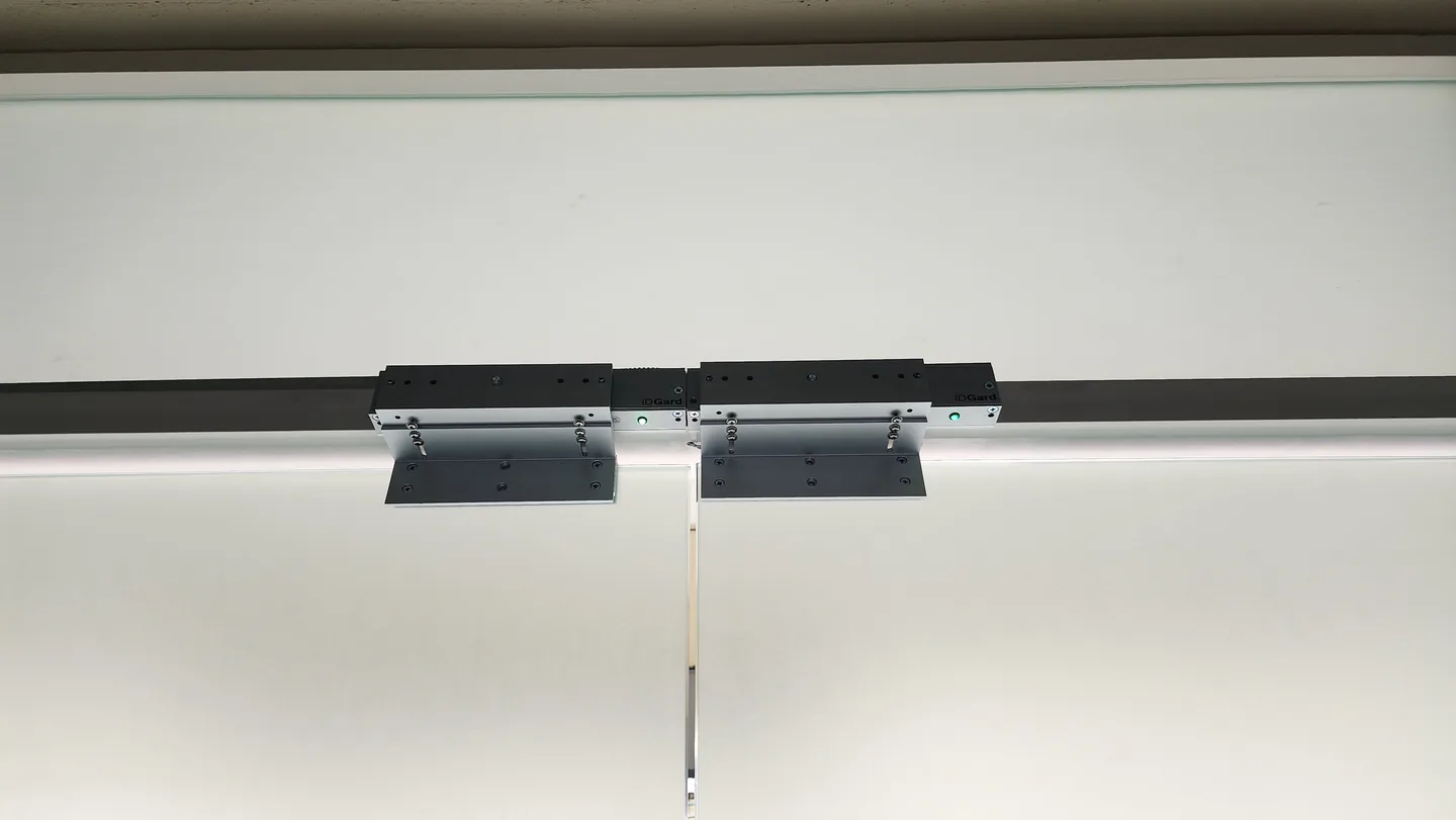 Pair of electromagnetic door locks mounted above glass double doors.