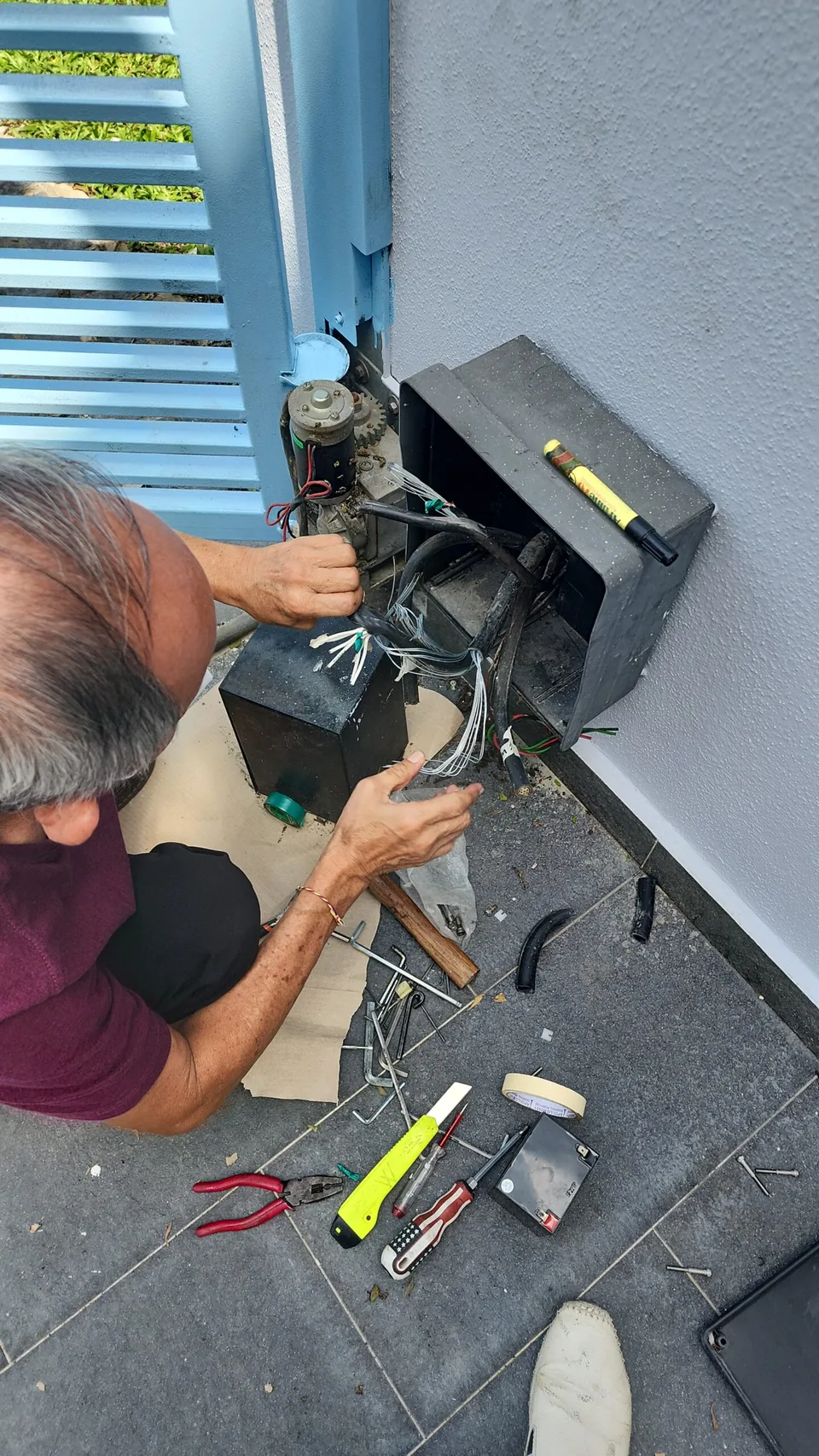 Technician works on a gate motor control housing beside the gate.