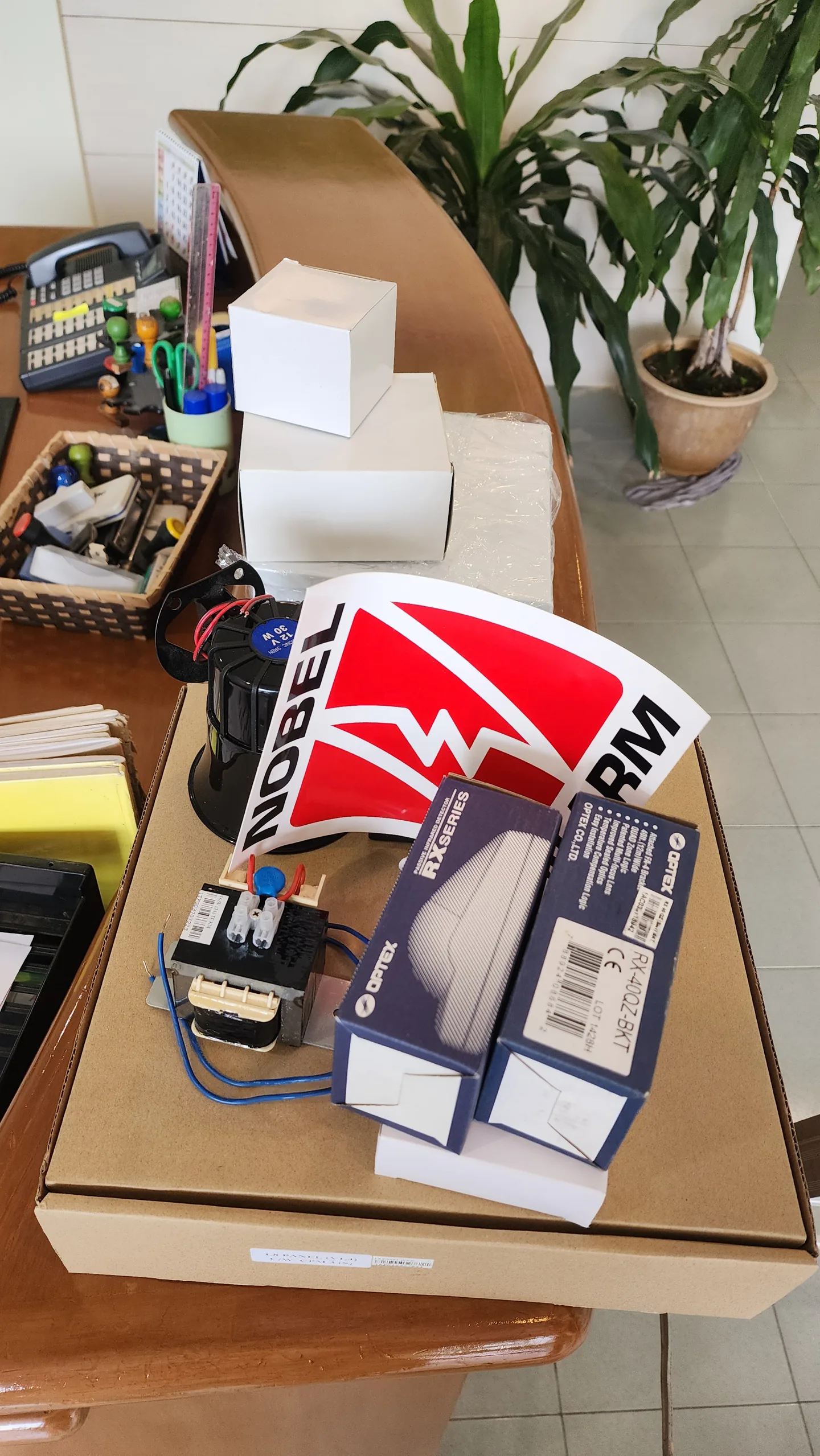Alarm control components and warning sign arranged on an office table.