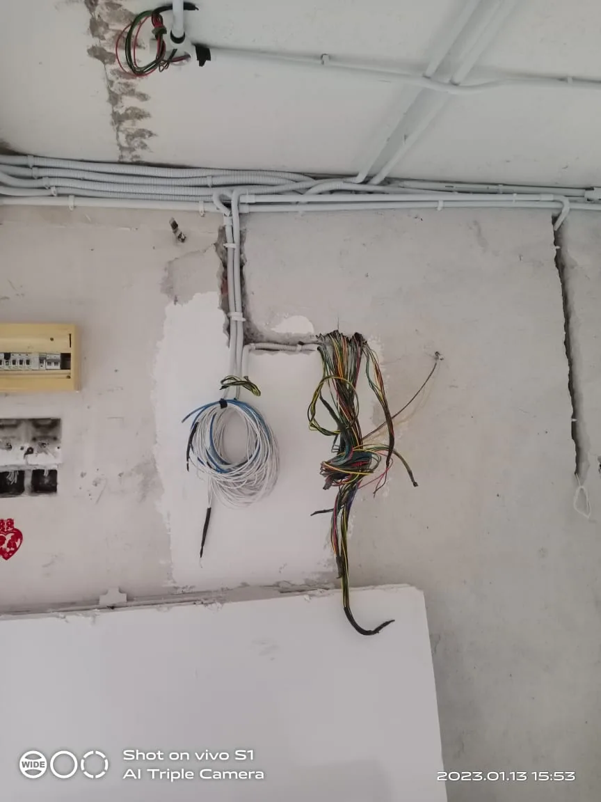 Coiled cable bundles and conduit on an unfinished wall.