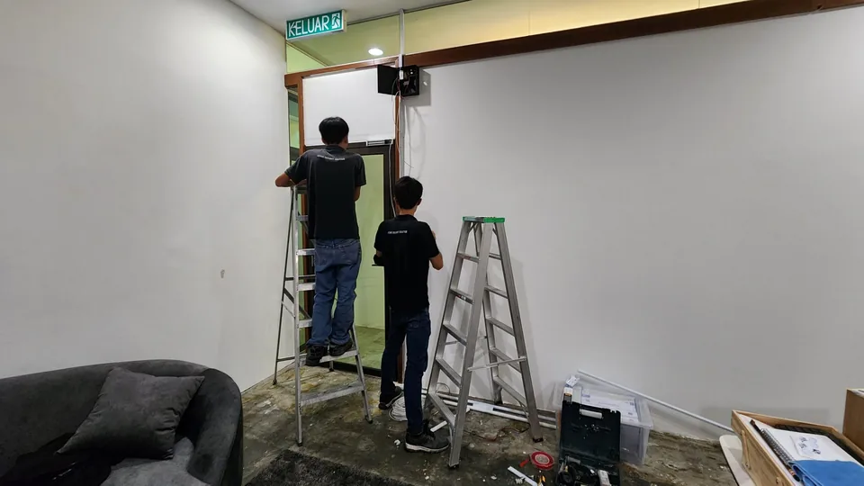 Technicians on ladders installing door hardware and cabling.
