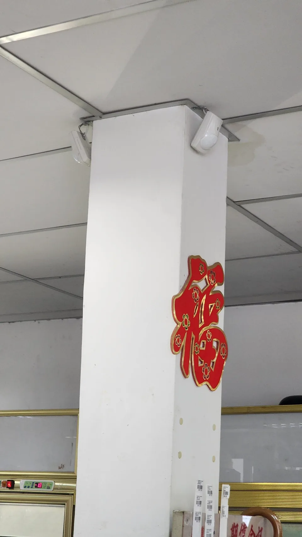 Two motion sensors mounted at the upper corners of an interior column.