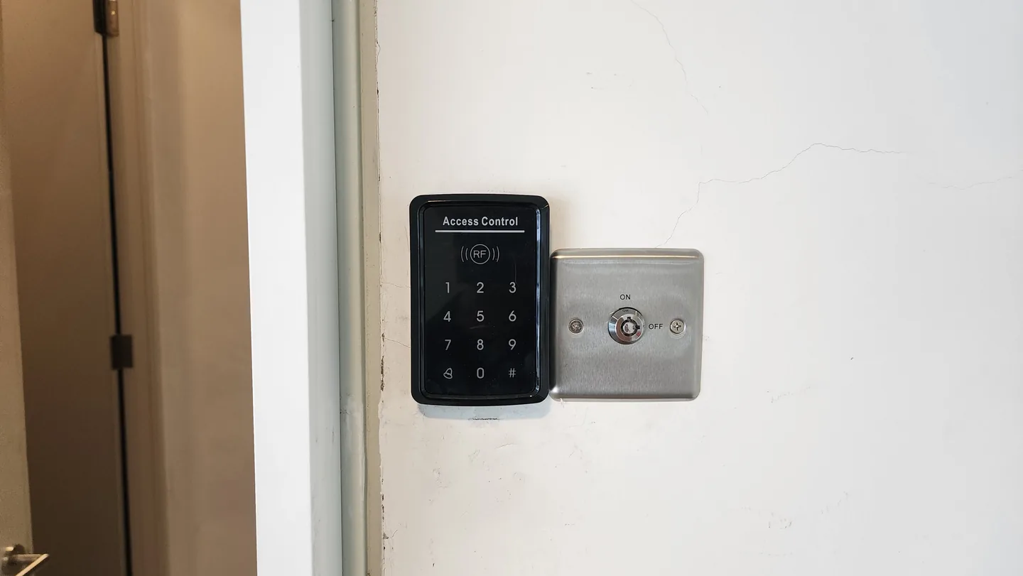Keypad access reader and door release button on a wall.