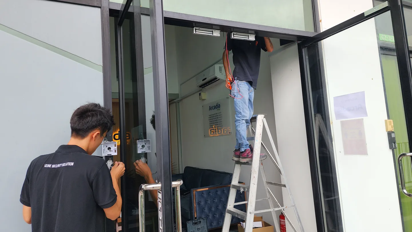 Two technicians installing access hardware around a glass entrance.