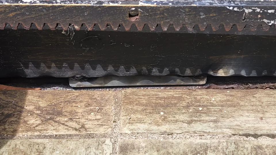 Close view of a worn gate rack and roller assembly.