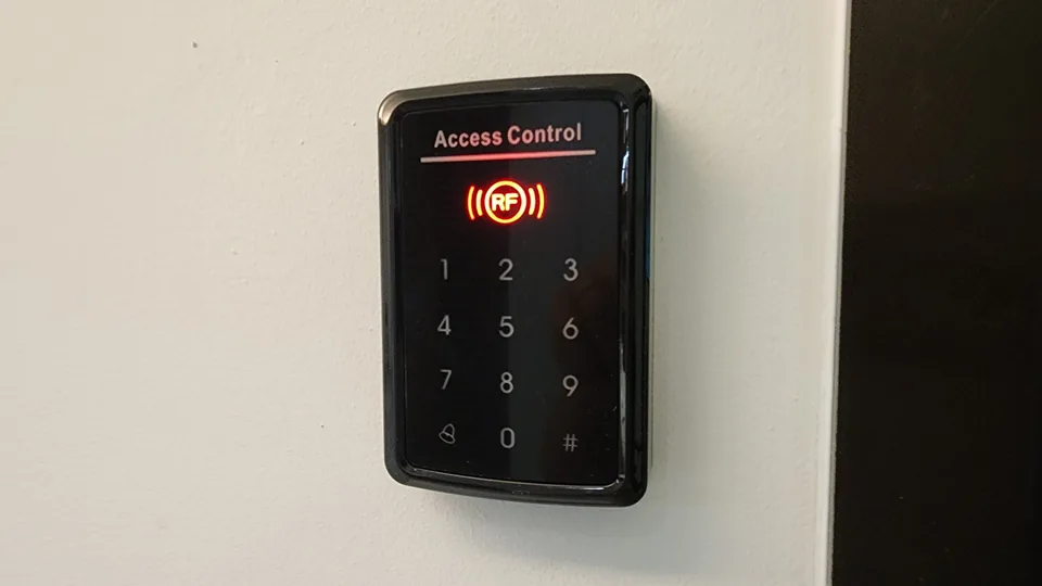 Illuminated keypad reader mounted beside a door.