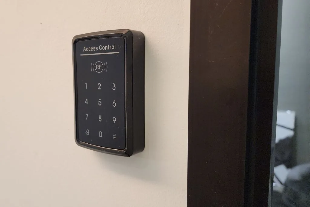 Wall-mounted keypad access reader beside a doorway