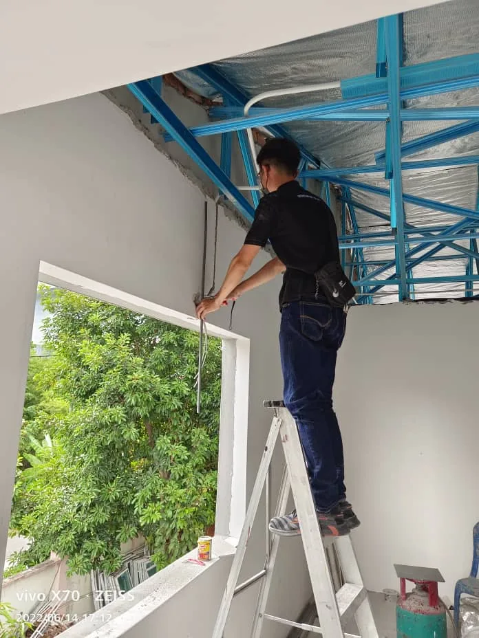 Technician works from a ladder beneath a blue metal canopy.