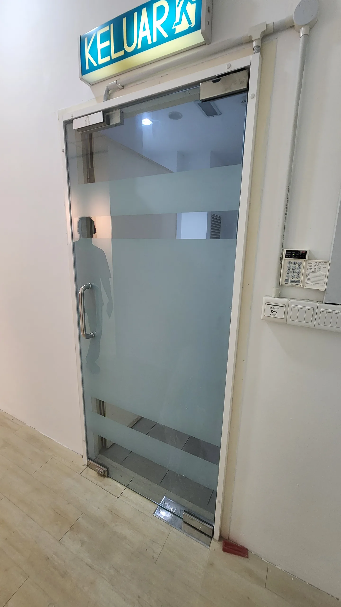 Frosted glass exit door with a keypad and door closer.